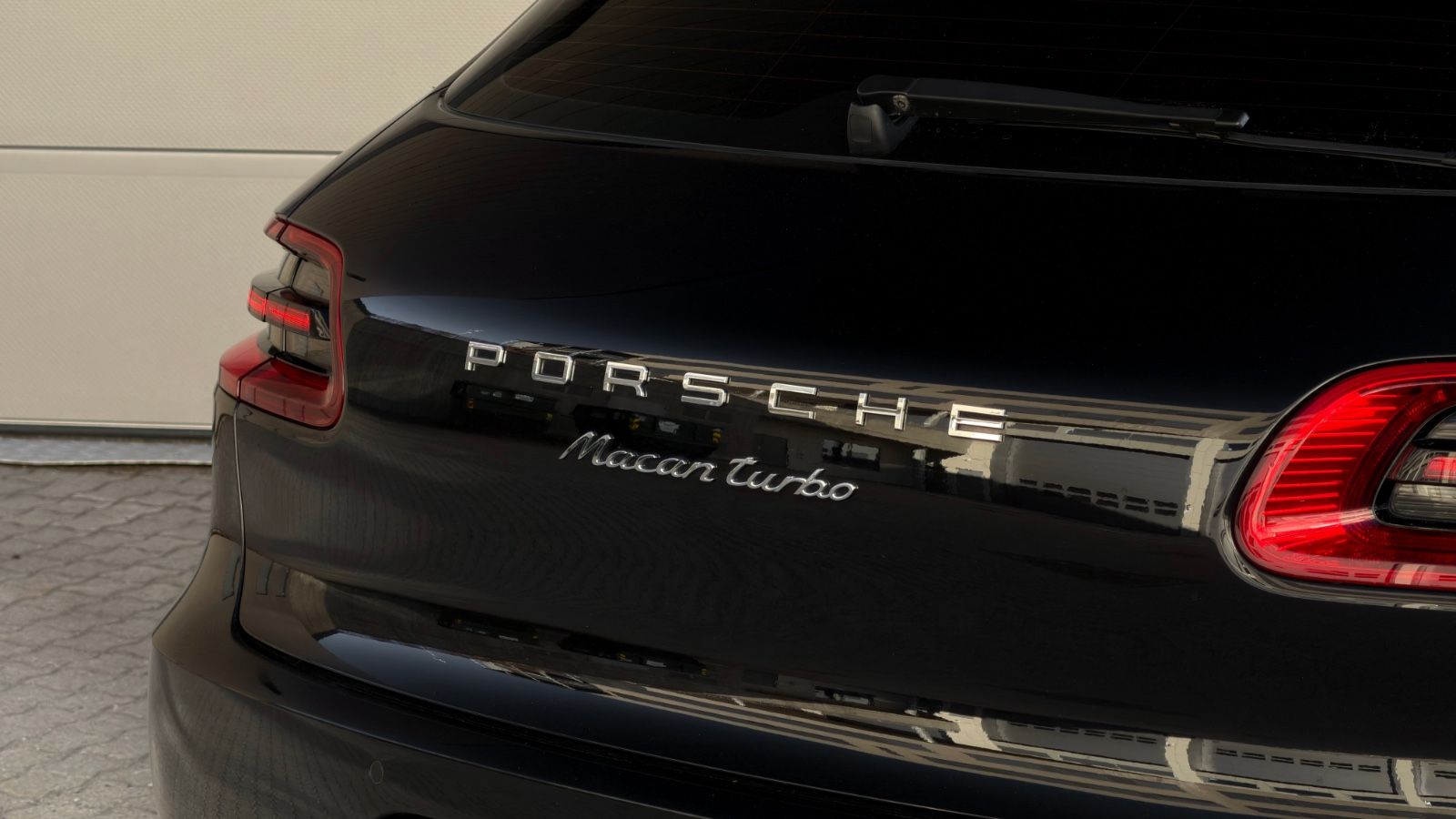 Porsche-logo på bakluken til en svart Porsche Macan Turbo